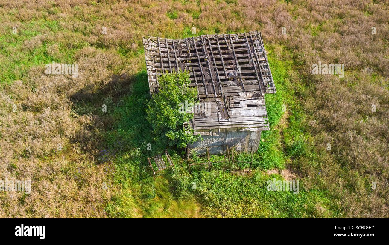 Aerial view of an old abandoned house with a collapsed roof, standing ...