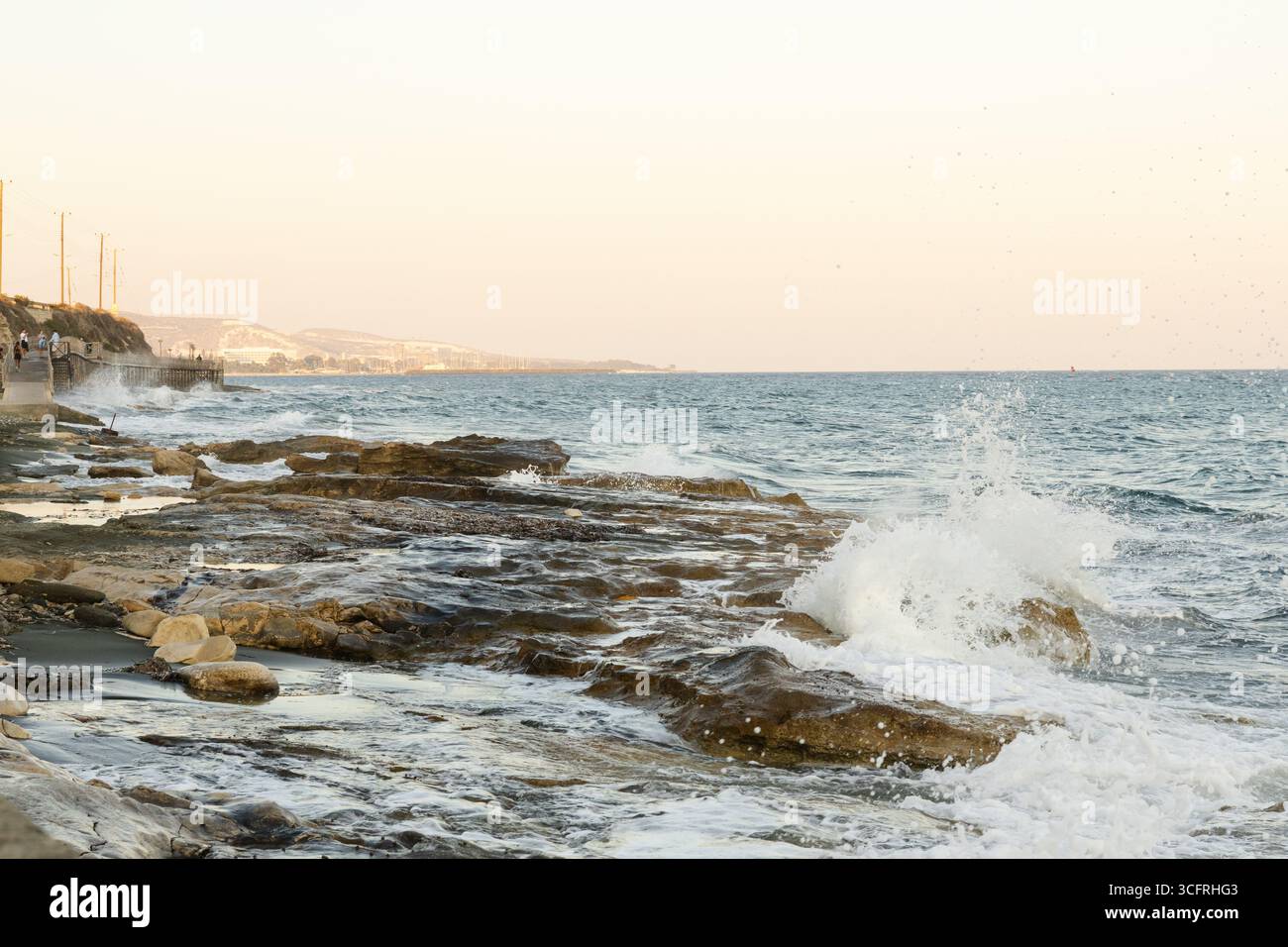 Waves breaking on the rocks at Limassol coastline at a summer afternoon Stock Photo
