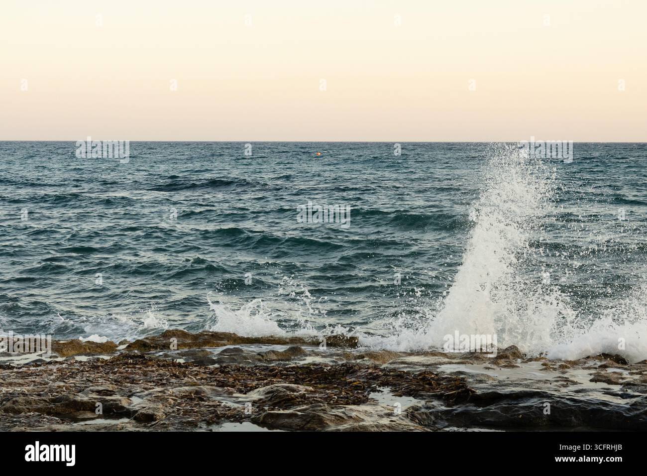 Waves breaking on the rocks at Limassol coastline at a summer afternoon Stock Photo