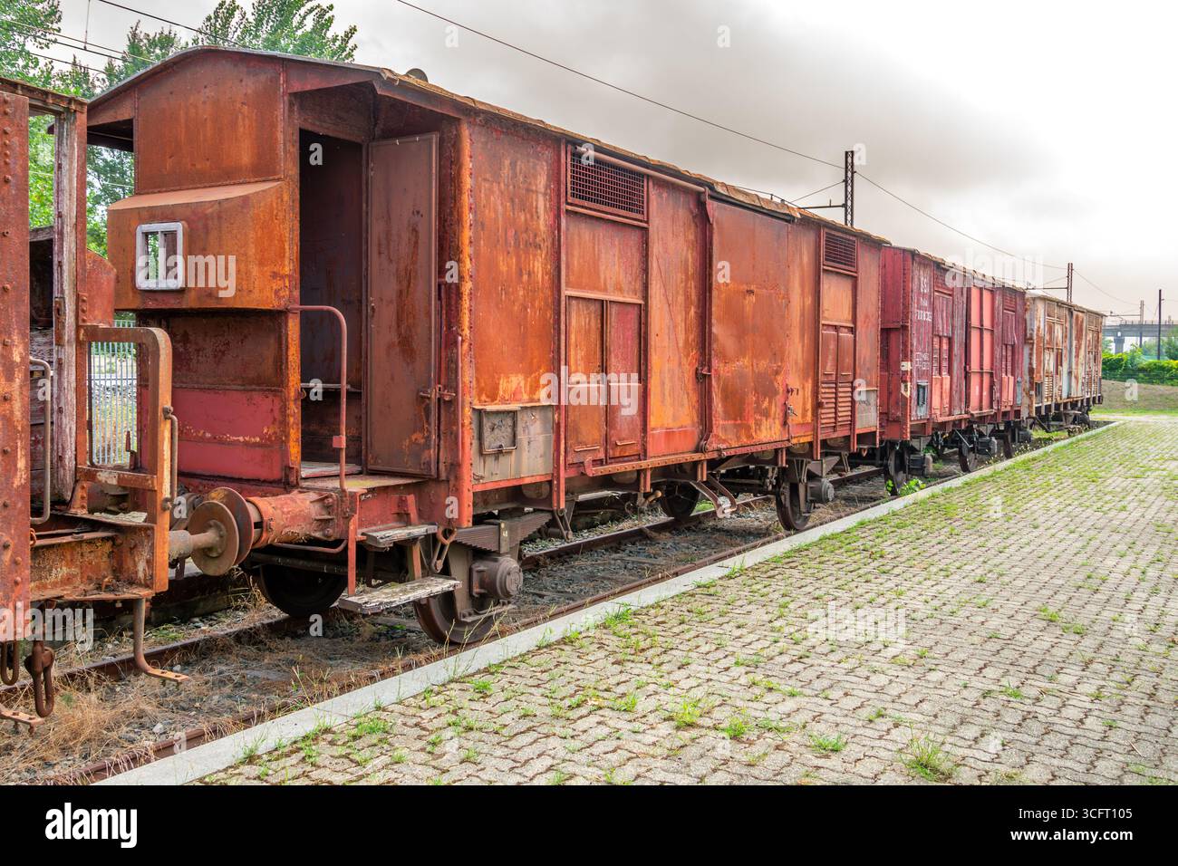 Old red G-type freight car with a braking cab. Old freight cars on tracks near the platform in  italian railway station Stock Photo