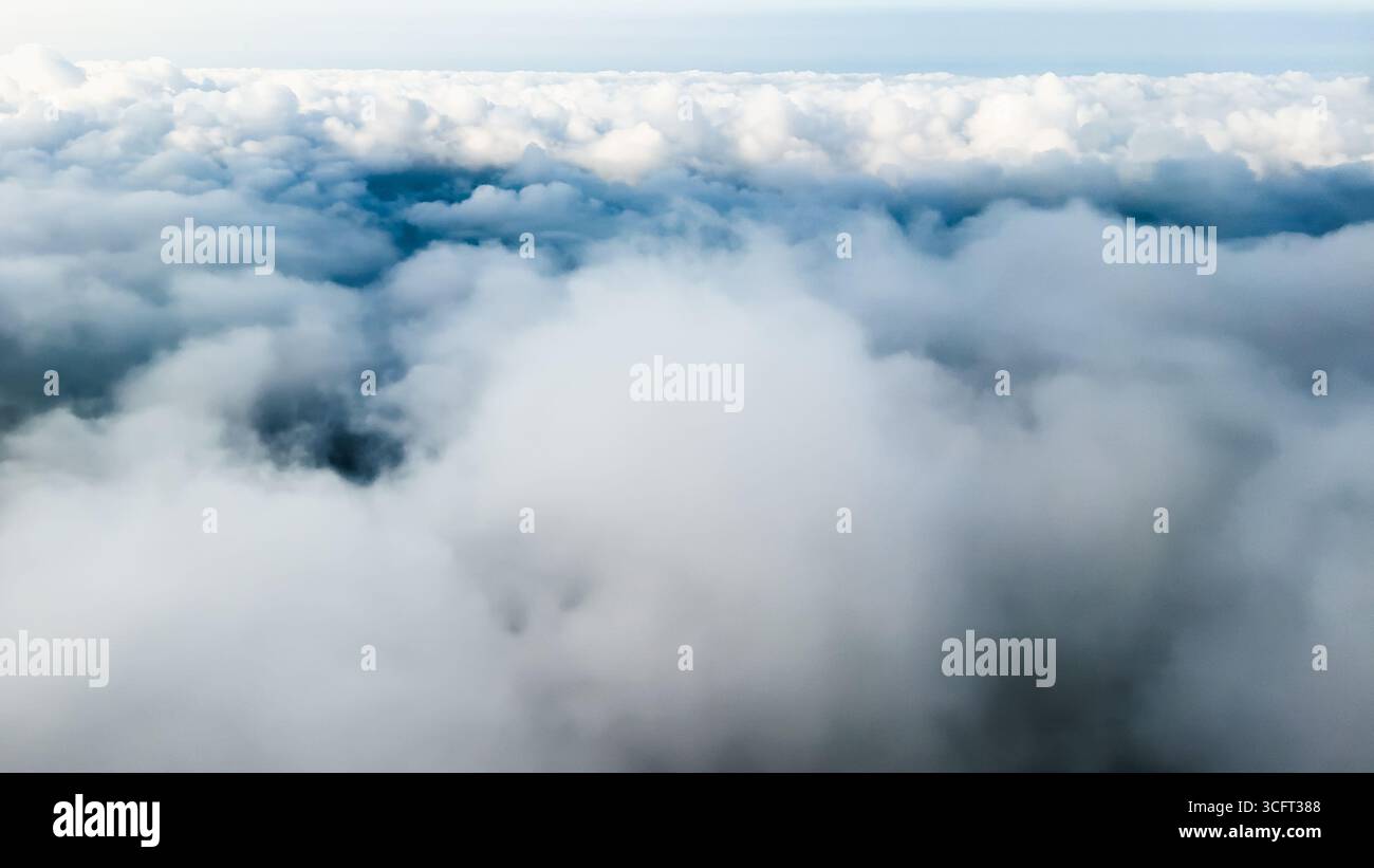 Billowy clouds fill the sky from an elevated perspective. Stock Photo