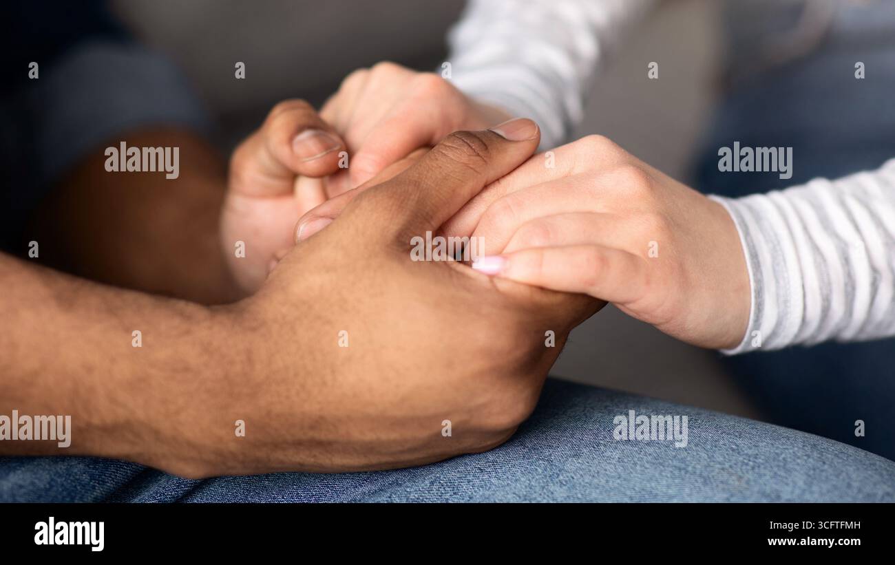 Cropped Image Of Romantic Interracial Couple Holding Hands Together Stock Photo