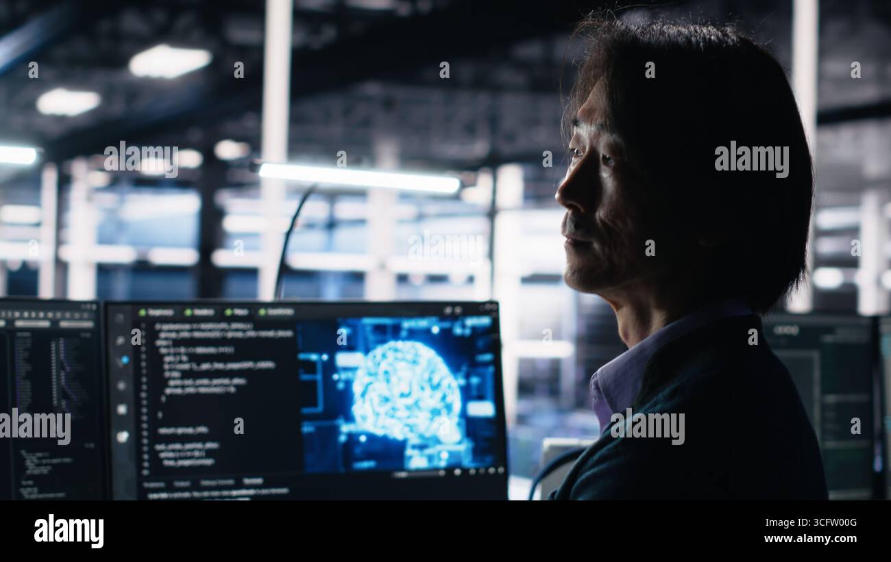 Data center software developer using computer to monitor neural network AI LLM visualization. Worker in high tech facility using PC to oversee servers powering machine learning processes, camera A Stock Photo