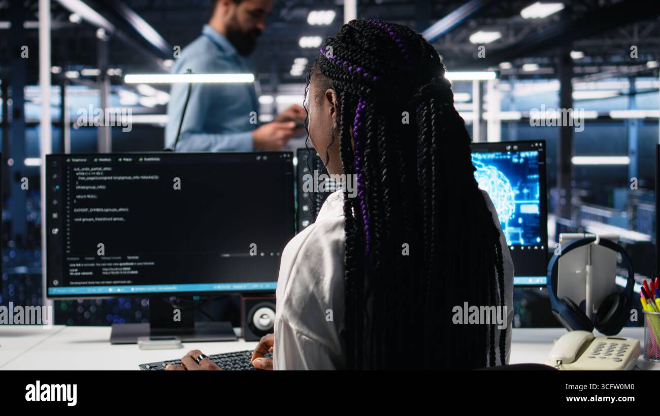 Technicians in data center review AI diagnostics, analyzing neural network performance to maintain operational reliability. IT workers optimize artificial intelligence systems configuration, camera A Stock Photo