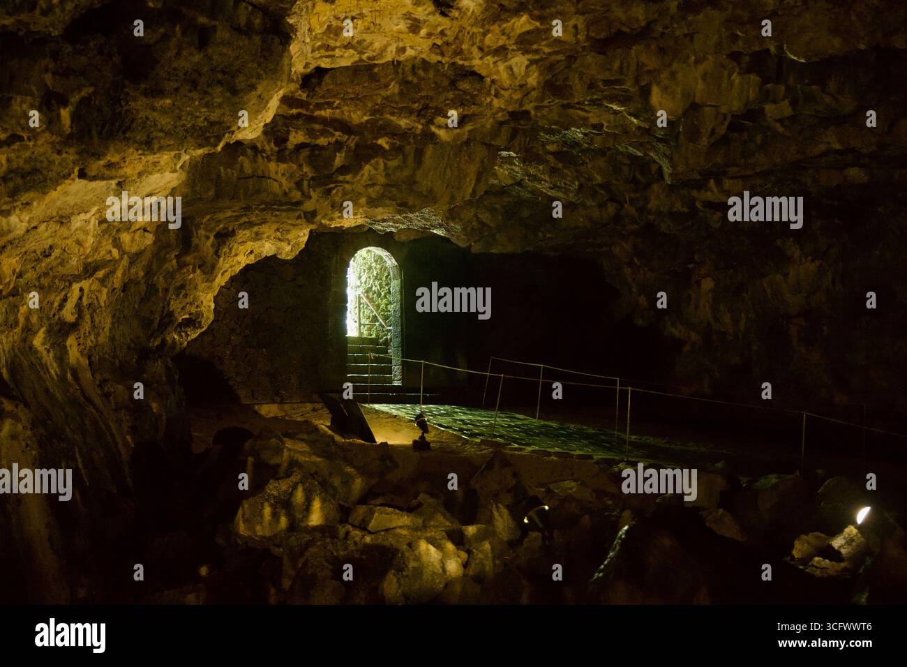 Guide Rope Cave A backlit arched doorway and steps glow at the end of a chamber inside ...