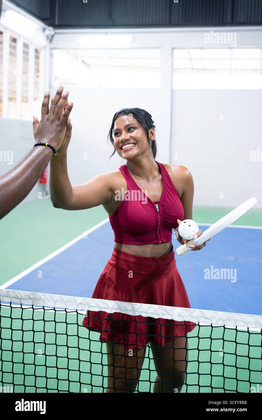 Happy Indian woman celebrating pickeball victory with high five Stock Photo