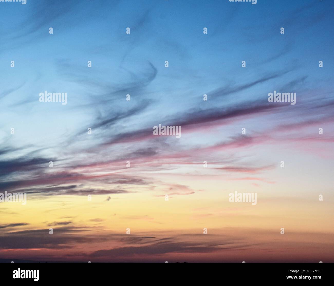 Magical sky during sunset with vivid hues and soft clouds glowing in warm evening light, ideal for backgrounds or design. Stock Photo