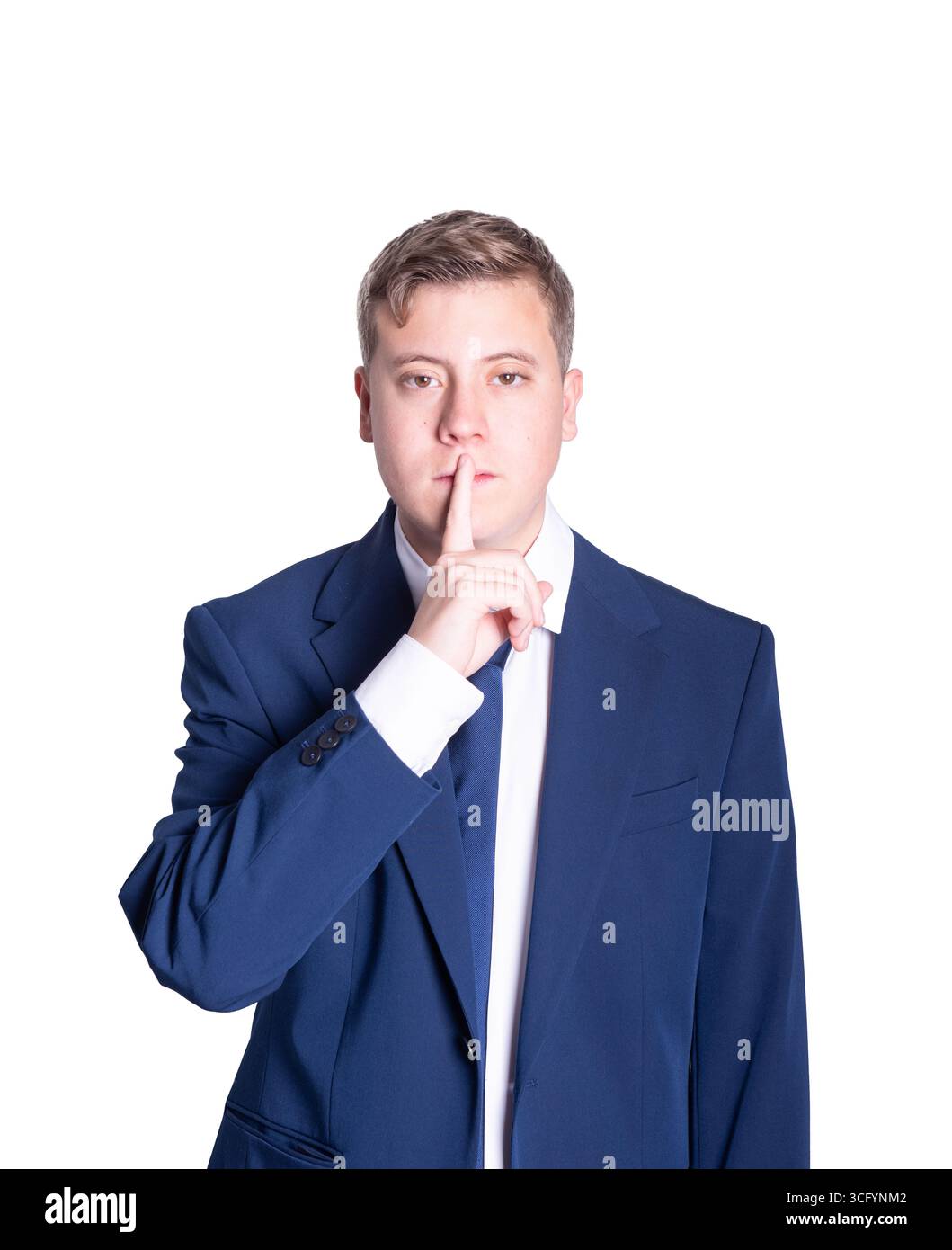 Male in a formal suit is making a shushing gesture, conveying a sense of secrecy and seriousness in a clean, minimalistic setting Stock Photo