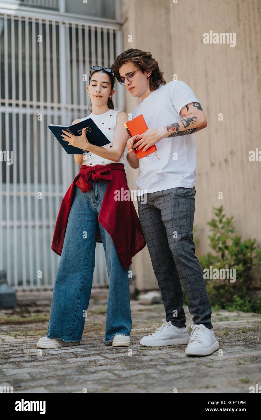 Two young adults collaborating while reviewing notes outdoors Stock Photo