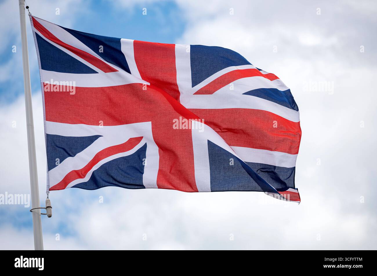 Union Jack flag fluttering in the wind with a blue sky and cloud ...