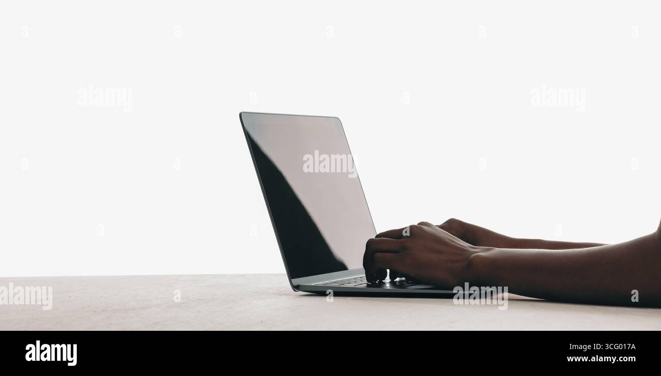 Close-up view of hands typing on a sleek modern laptop placed on a flat surface. Stock Photo