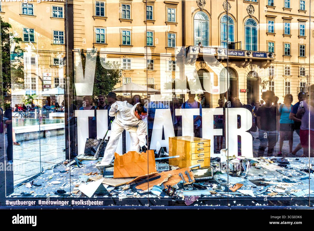 'Volks Theater' (People's Theatre) performer smashing computer equipment in large glass cubicle in Museum Quarter - Vienna, Austria.  Captions are pro Stock Photo