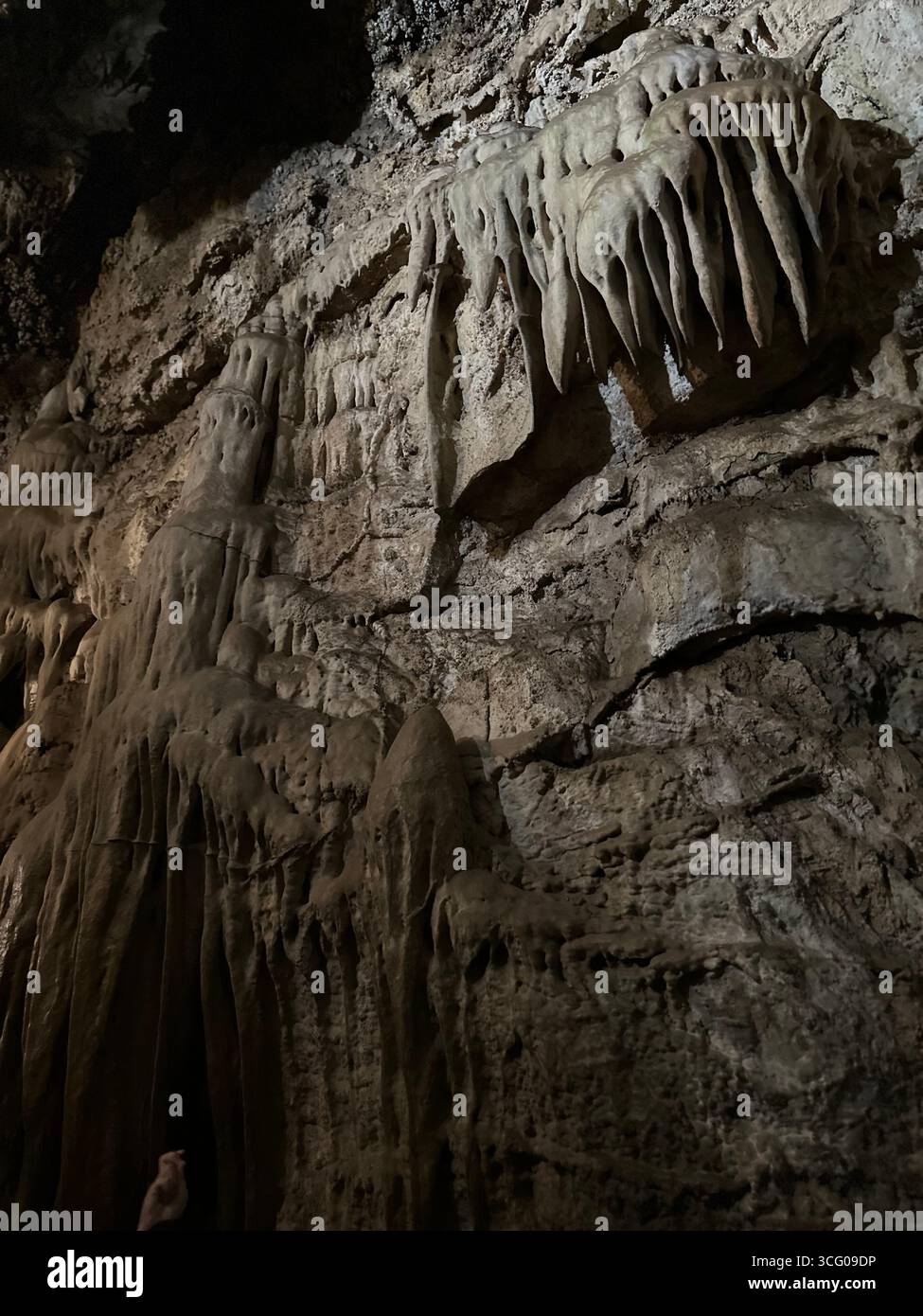 Detailed view of intricate stalactites and flowstone formations inside a limestone cave, showcasing the natural beauty and geological features - Smartphone Captured Stock Image