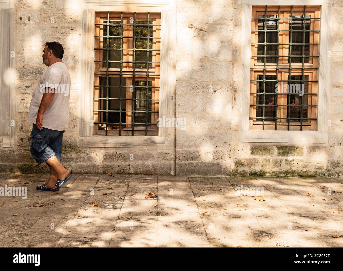 Older man casually walking near a traditional turkish stone wall Stock Photo