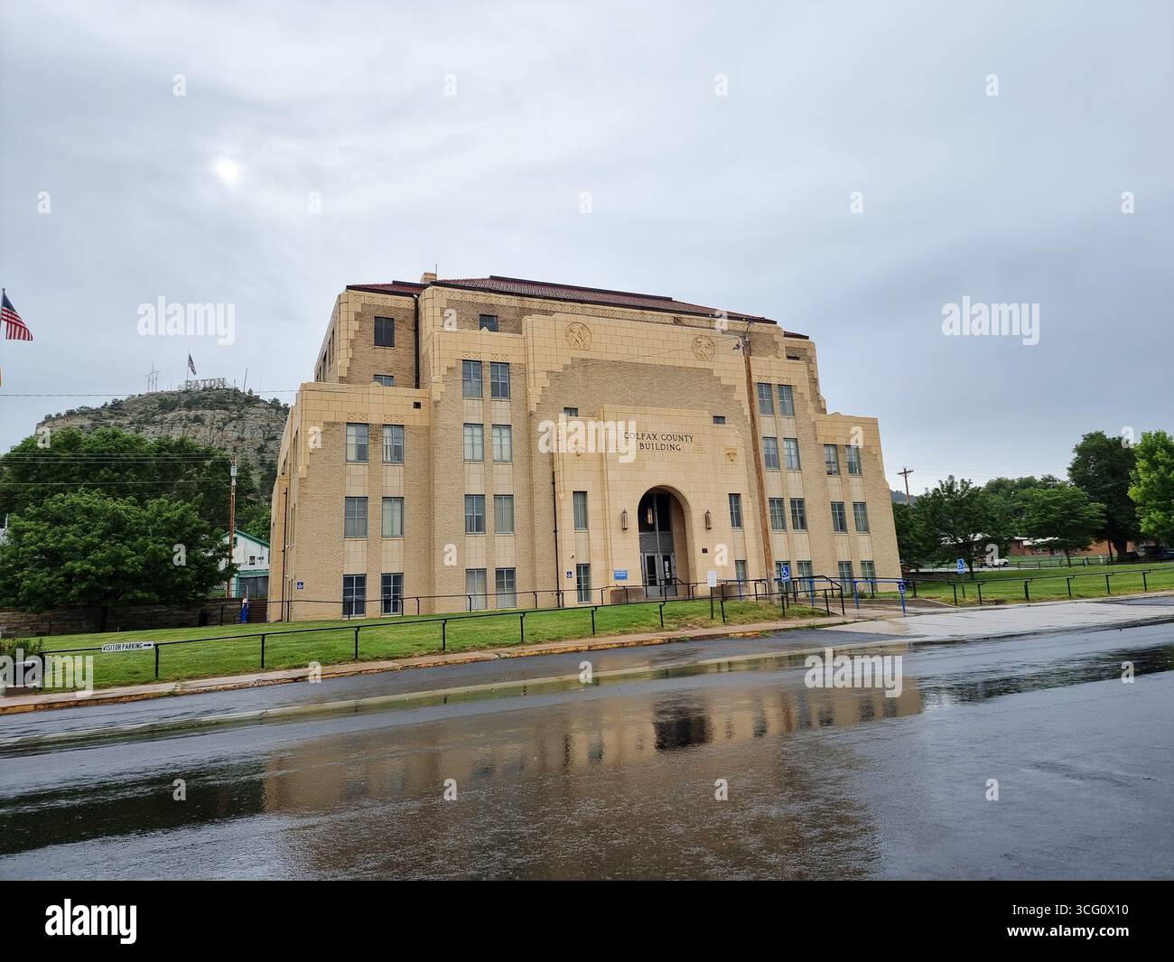 Historic Colfax County Courthouse building in Raton, New Mexico, U.S.A. on a rainy day; Raton sign on hill in background - Smartphone Captured Stock Image Historic Colfax County Courthouse building in Raton, New Mexico, U.S.A. on a rainy day; Raton sign on hill in background - Smartphone Captured Stock Image