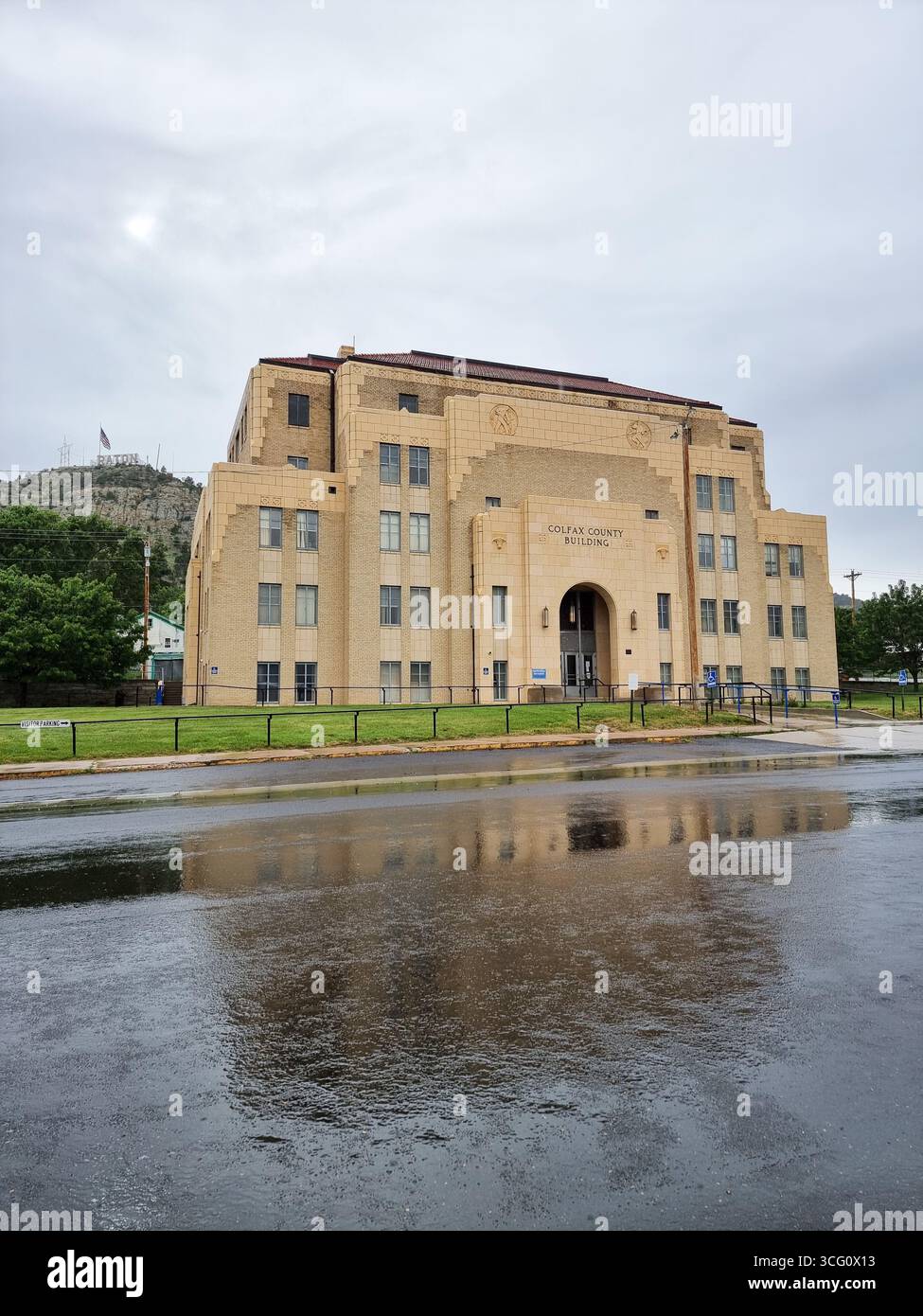 Historic Colfax County Courthouse building in Raton, New Mexico, U.S.A. on a rainy day; Raton sign on hill in background - Smartphone Captured Stock Image Historic Colfax County Courthouse building in Raton, New Mexico, U.S.A. on a rainy day; Raton sign on hill in background - Smartphone Captured Stock Image