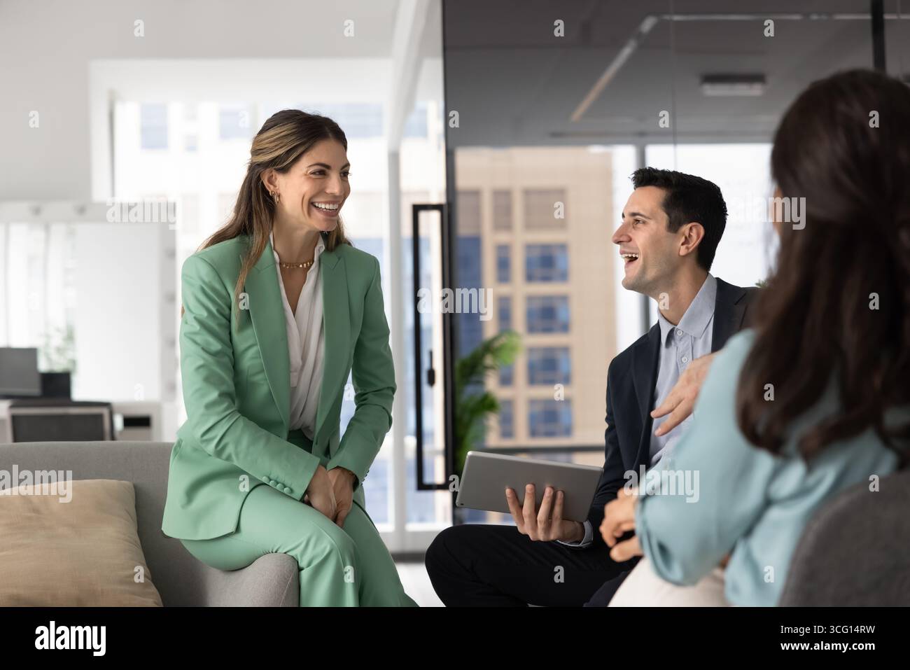Three young professionals engaged in positive conversation Stock Photo