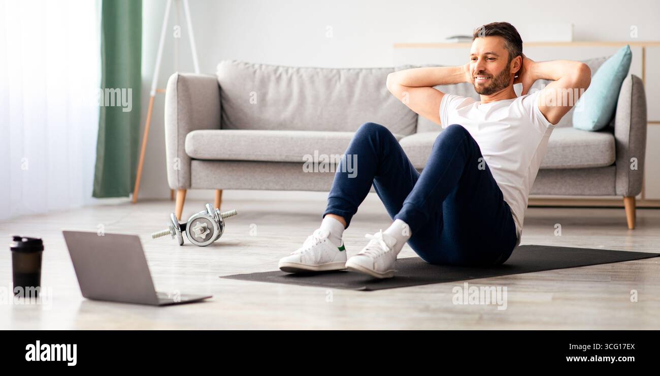 Smiling man working on abs, using laptop Stock Photo