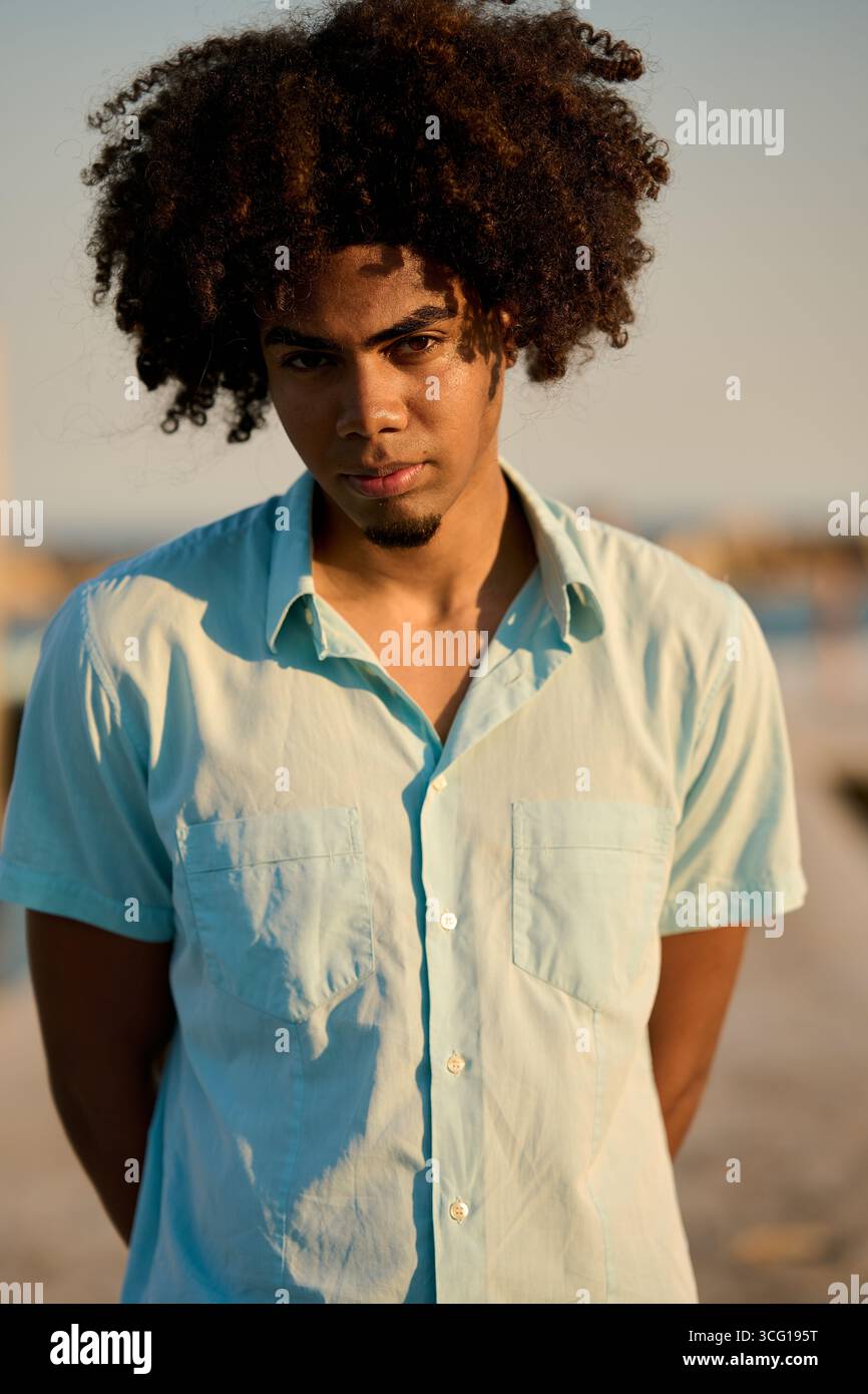 Young man with afro hair looking confident at sunset Stock Photo