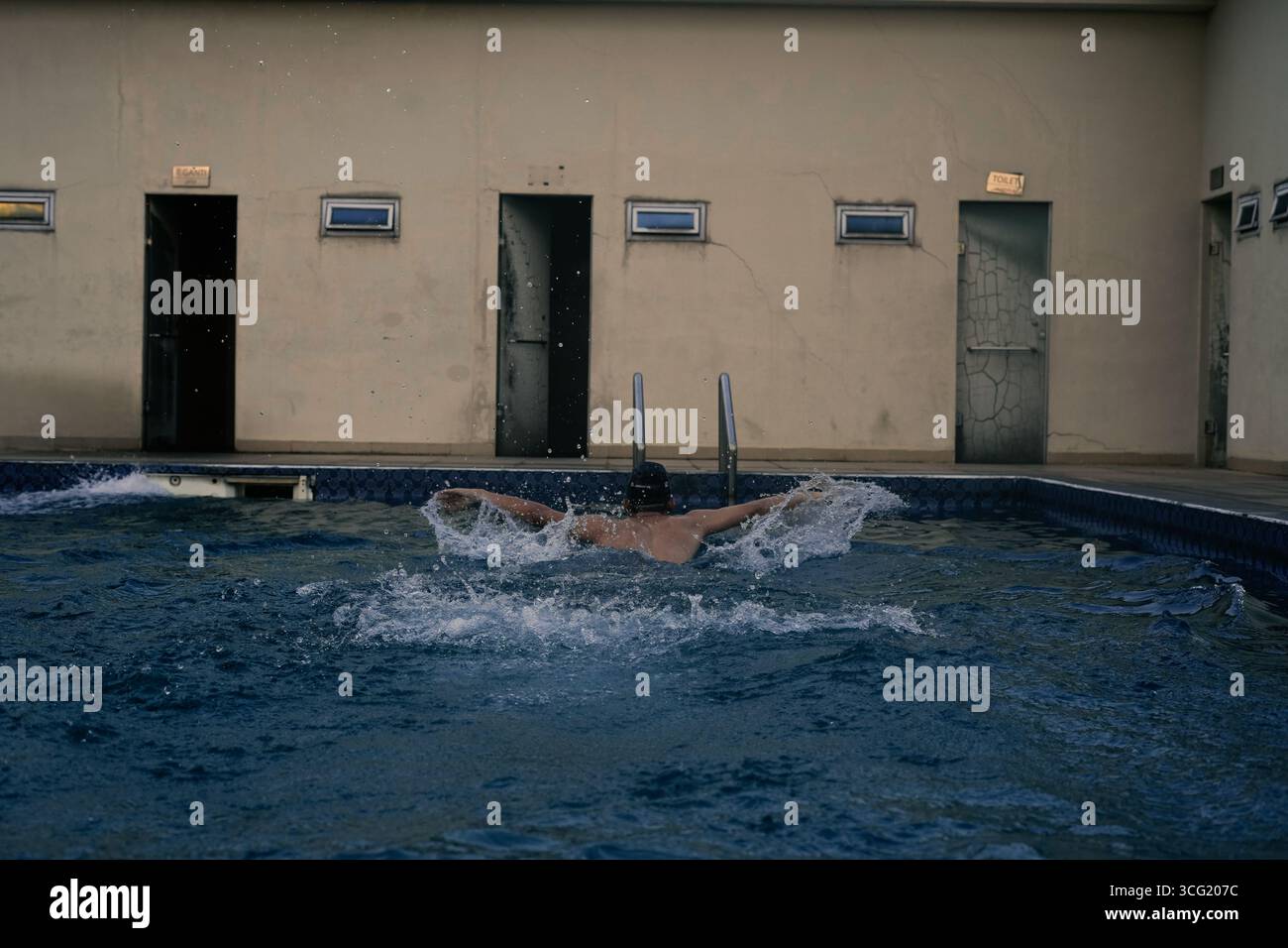 A swimmer is practicing the butterfly stroke in a serene outdoor ...