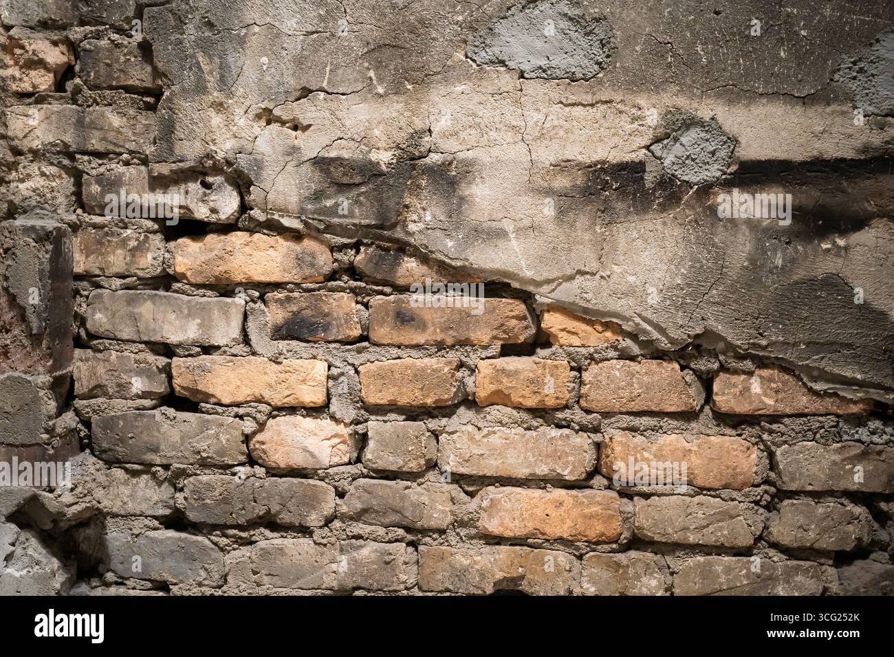 A detailed view of an old brick wall with noticeable cracks and weathered texture, showcasing urban decay and industrial aesthetics. Stock Photo