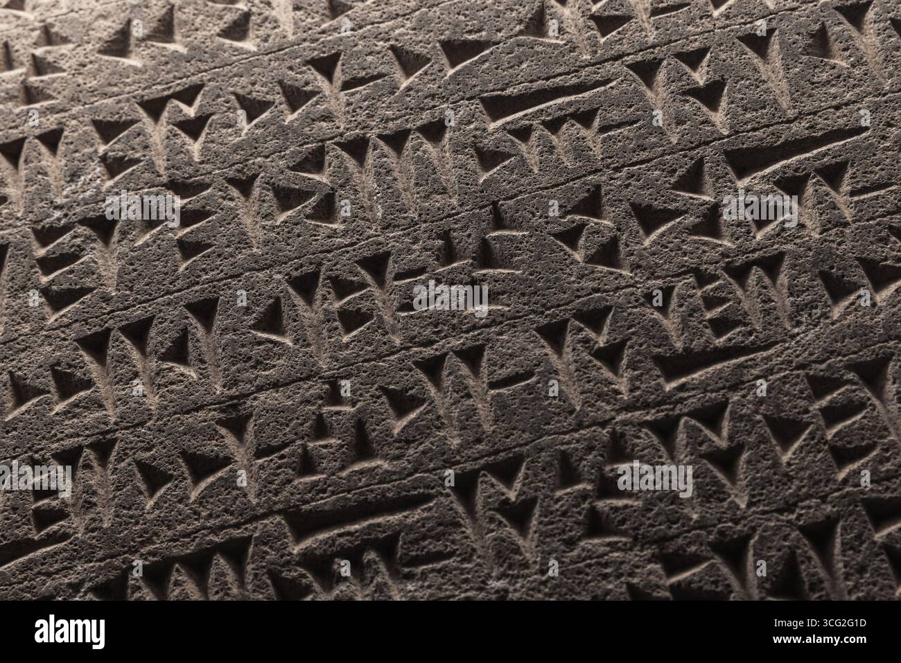 Detailed close-up of ancient Sumerian cuneiform script etched into a stone.Cuneiform is a logo-syllabic writing system that was used to write several Stock Photo