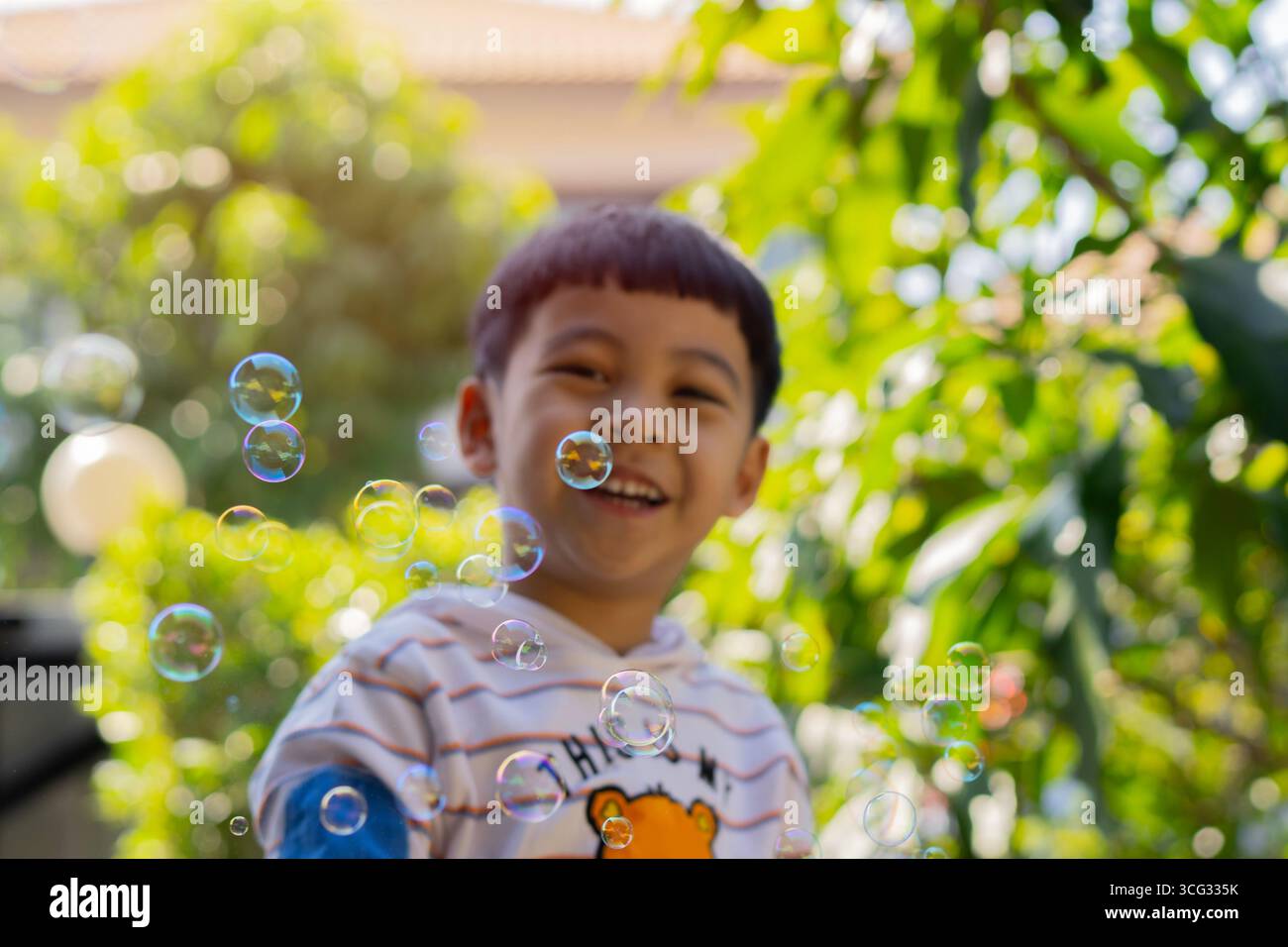 Child and Soap Bubbles Concept. Happy child blowing bubbles in park. Selective focus. Stock Photo