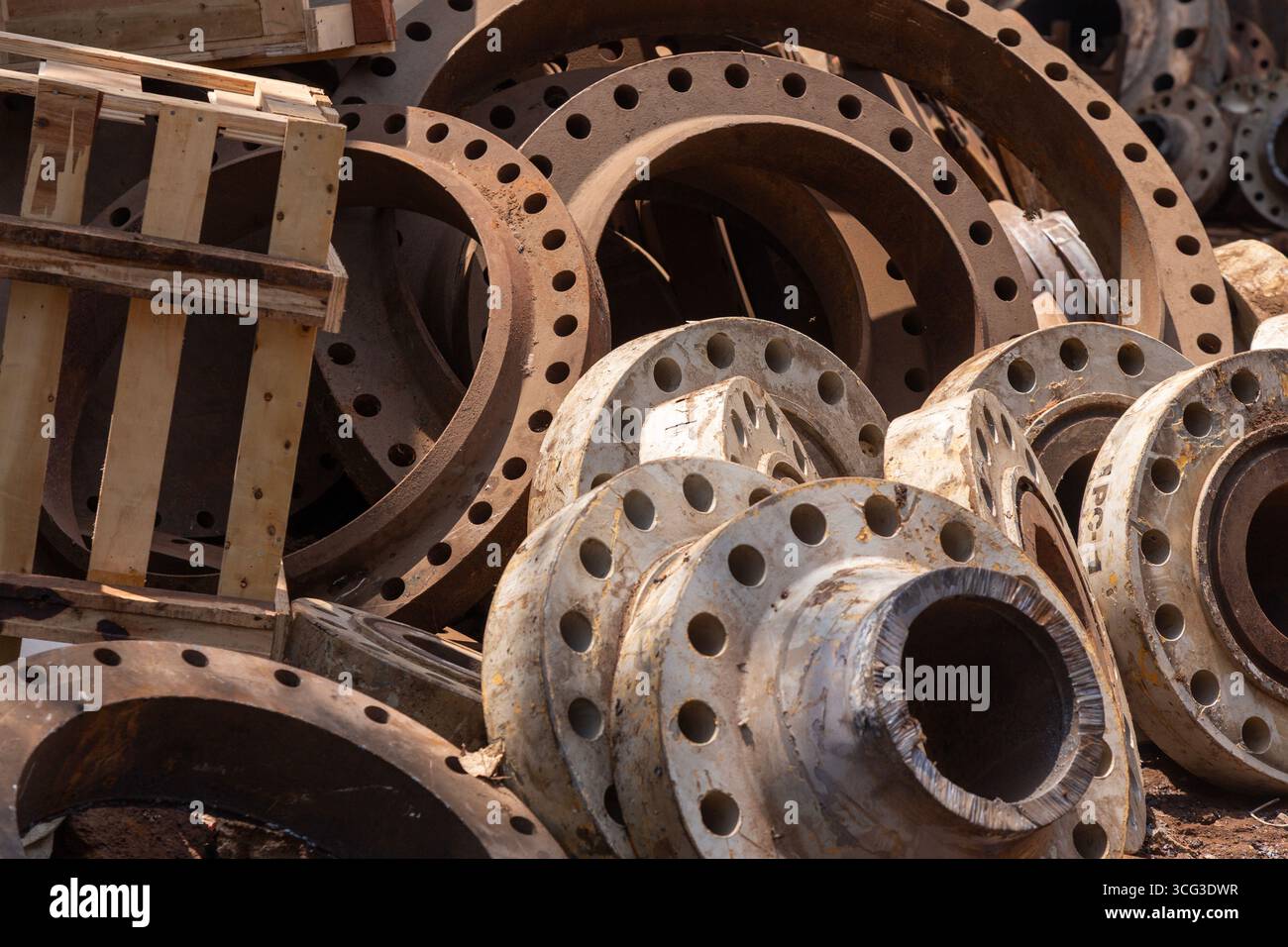 Stacking Flanges This image displays a stack of rusty and weathered metal flanges with ...