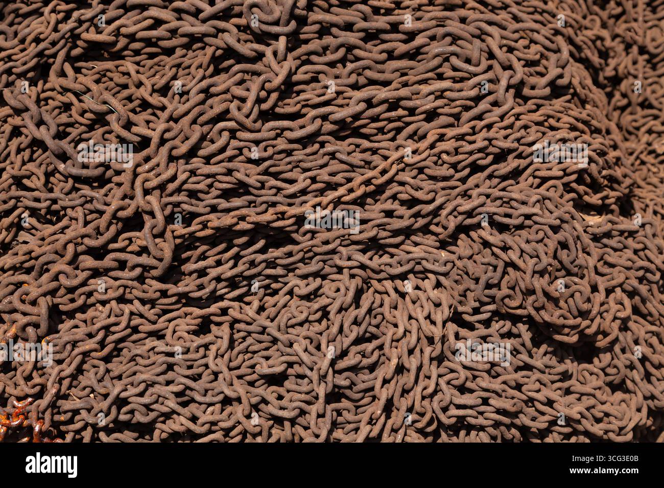 This image displays a dense pile of rusted metal chains, emphasizing industrial decay and the texture of corroded iron links Stock Photo