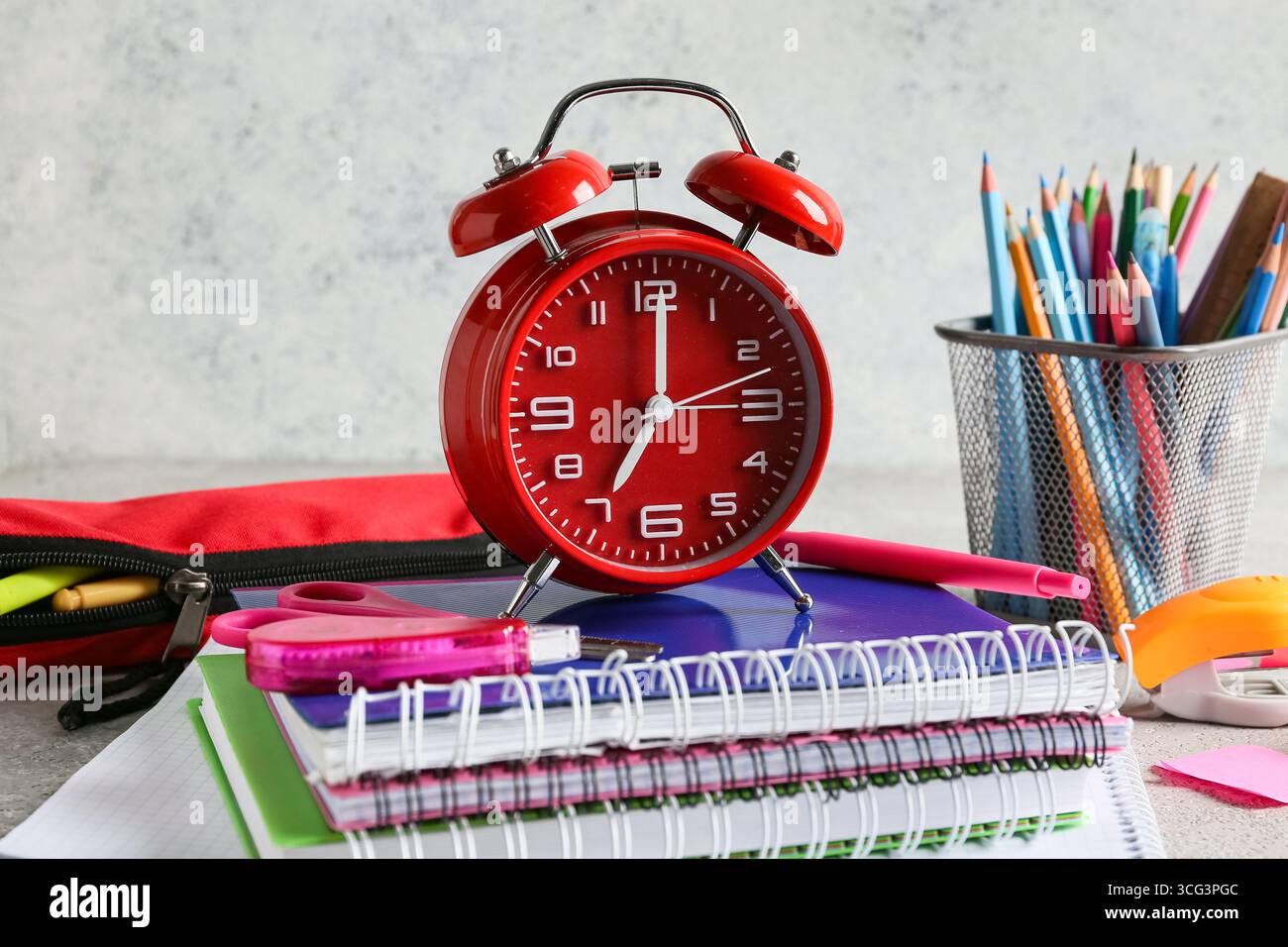 Alarm clock and notebooks on table against grey background Stock Photo