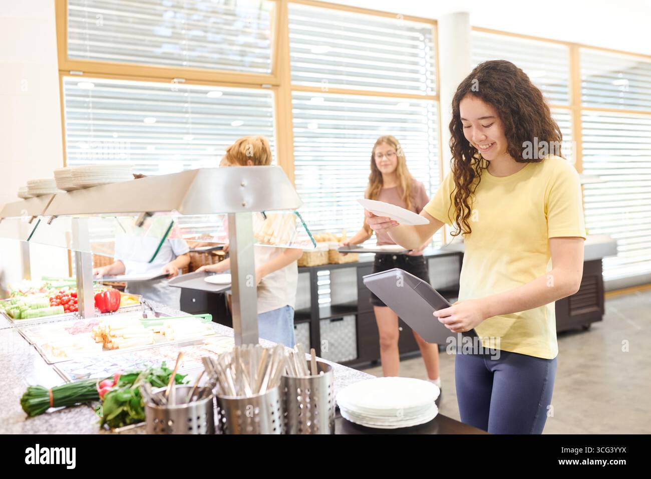 A group of students gather in a clean and modern cafeteria, preparing ...