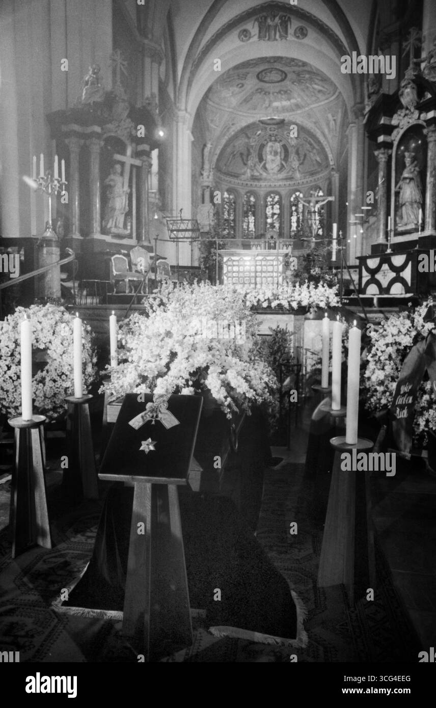 Sarg von Mildred Scheel ist im Bonner Münster feierlich aufgebahrt, umgeben von weißen Blumenkränzen und Kerzen. Im Vordergrund liegt das Bundesverdienstkreuz mit Stern auf Samt. Der festlich geschmückte Altarraum bildet den Hintergrund dieser zentralen Szene des Trauergottesdienstes. Stock Photo