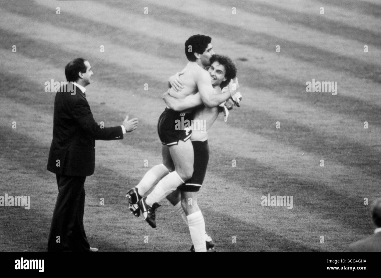 Nach dem Viertelfinalsieg bei der WM 1990 hebt Oscar Ruggeri den jubelnden Diego Maradona in die Höhe. Beide stehen mit freiem Oberkörper auf dem Rasen. Stock Photo