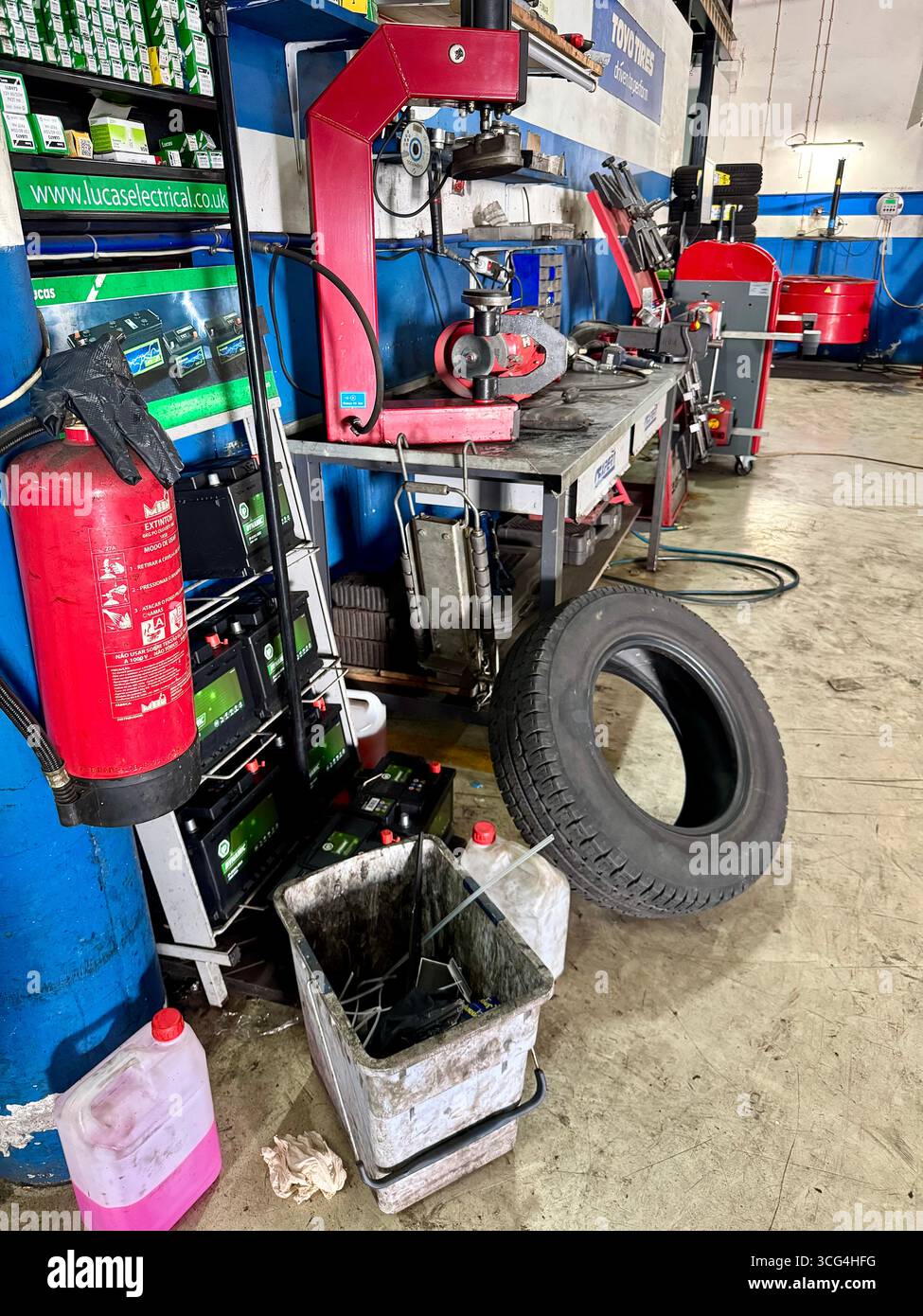 Busy automotive repair workshop with tire, fire extinguisher, and various tools and equipment. - Smartphone Captured Stock Image