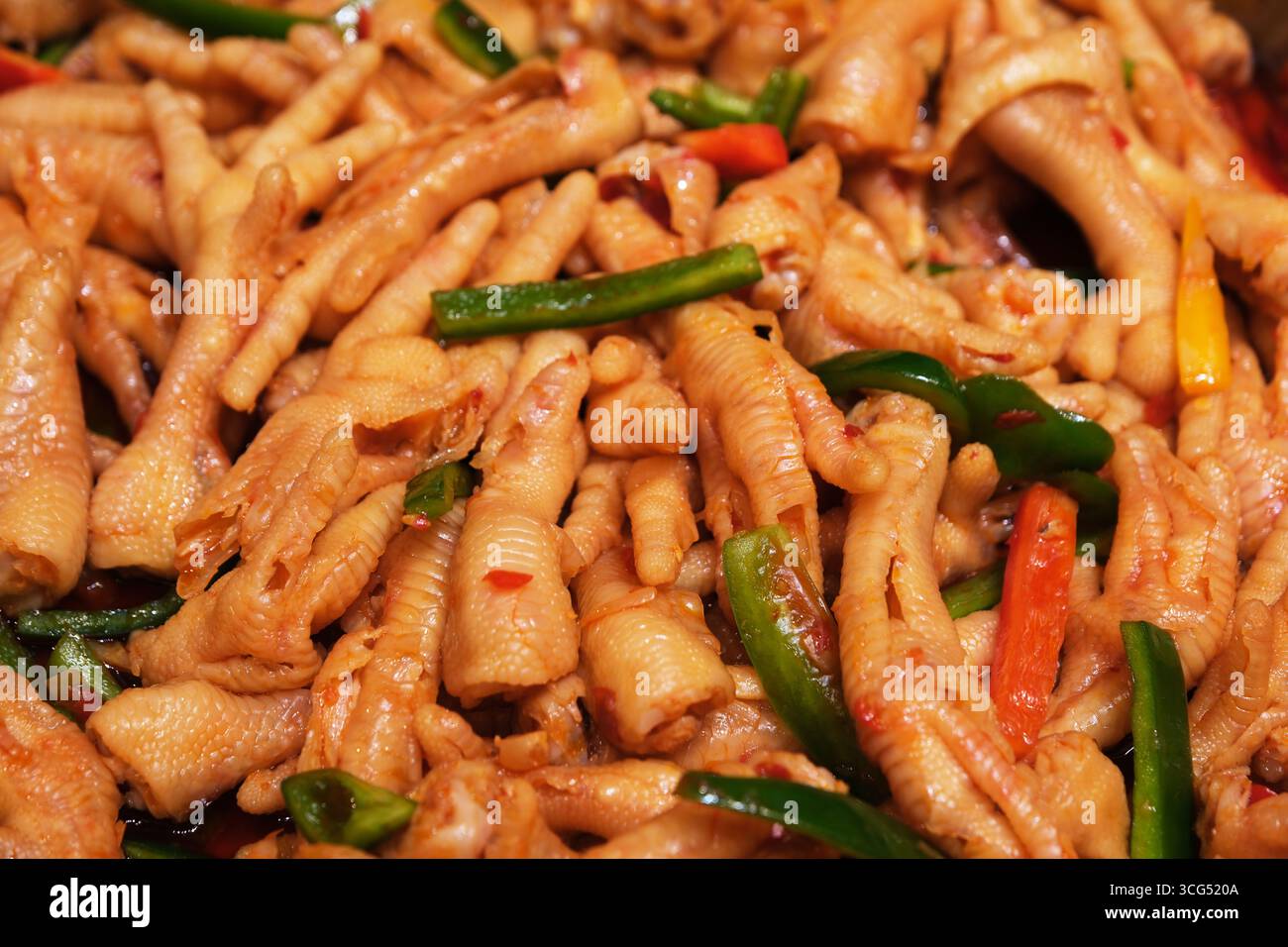 Close-up of stacked chicken feet mixed with green and red peppers, Chinese food Stock Photo