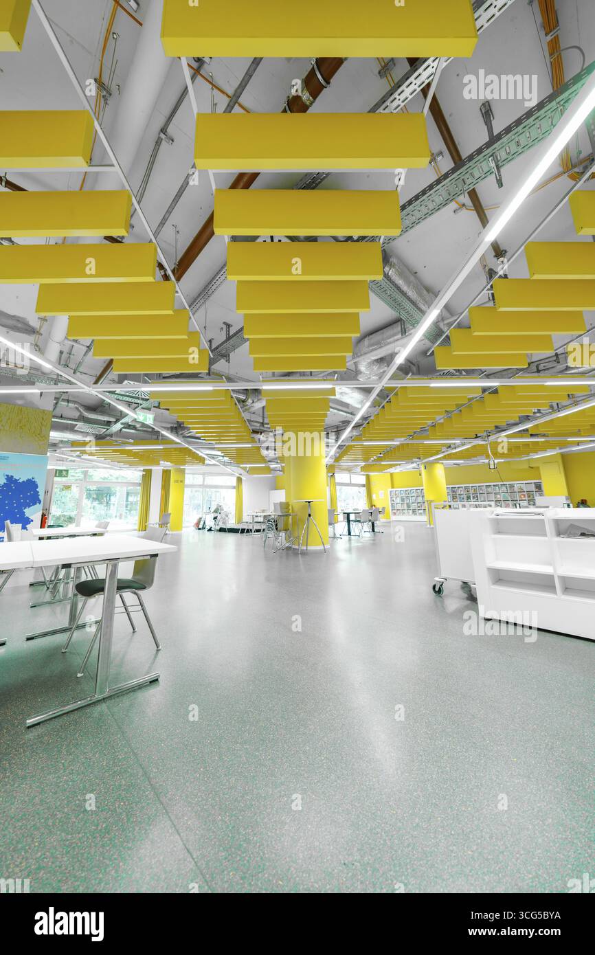 Modern library with yellow design elements, workstations and open ...