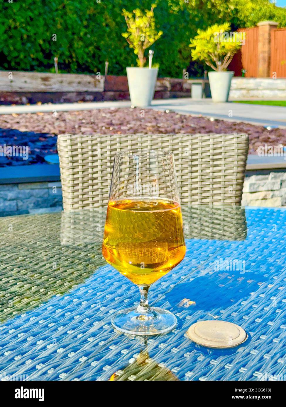 Glass of golden lager beer on a table in a garden - Smartphone Captured Stock Image