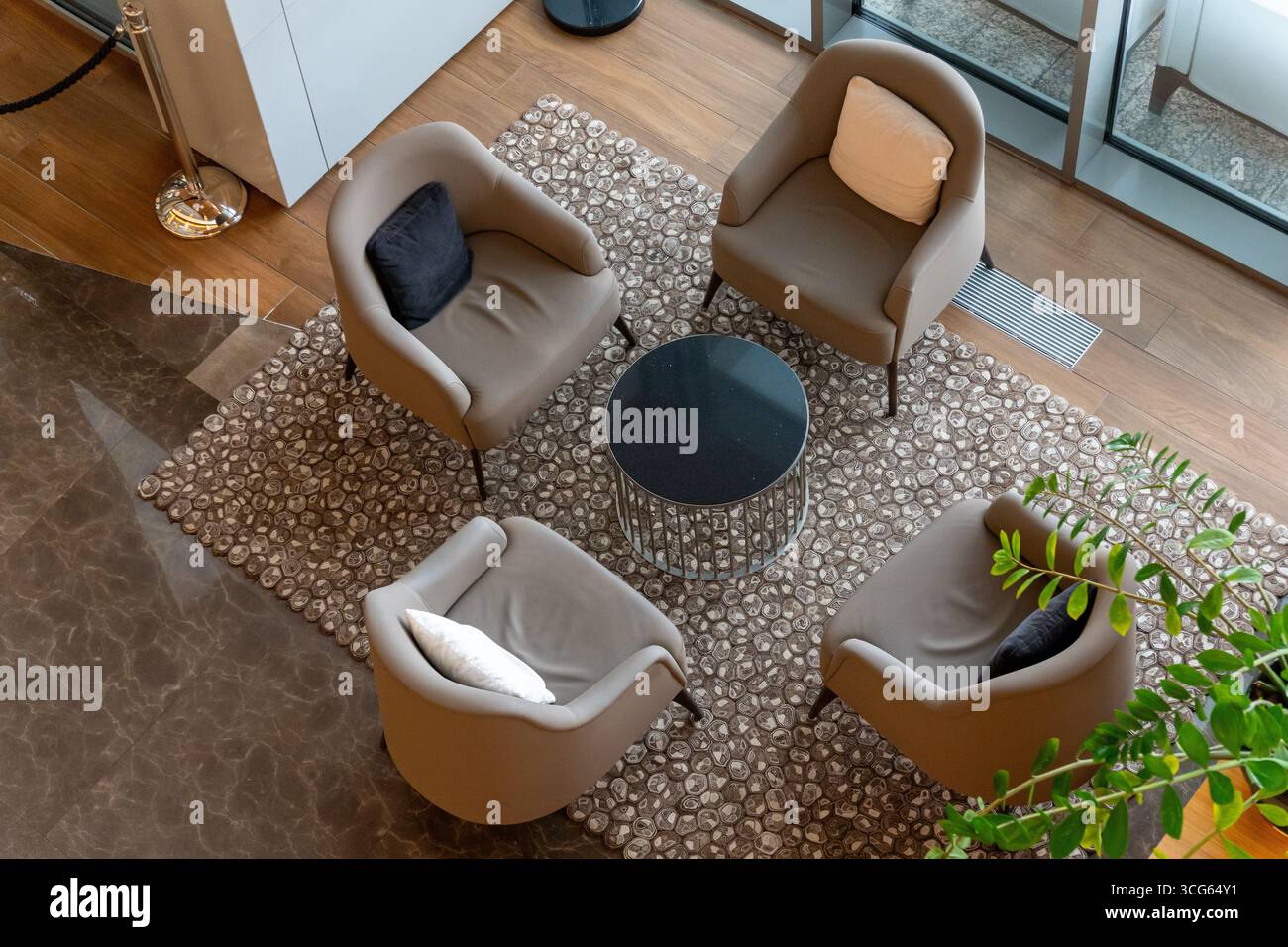 A modern hotel lobby with four plush armchairs and a meeting table, captured in a minimalist top-down aerial view on a soft carpet. Stock Photo
