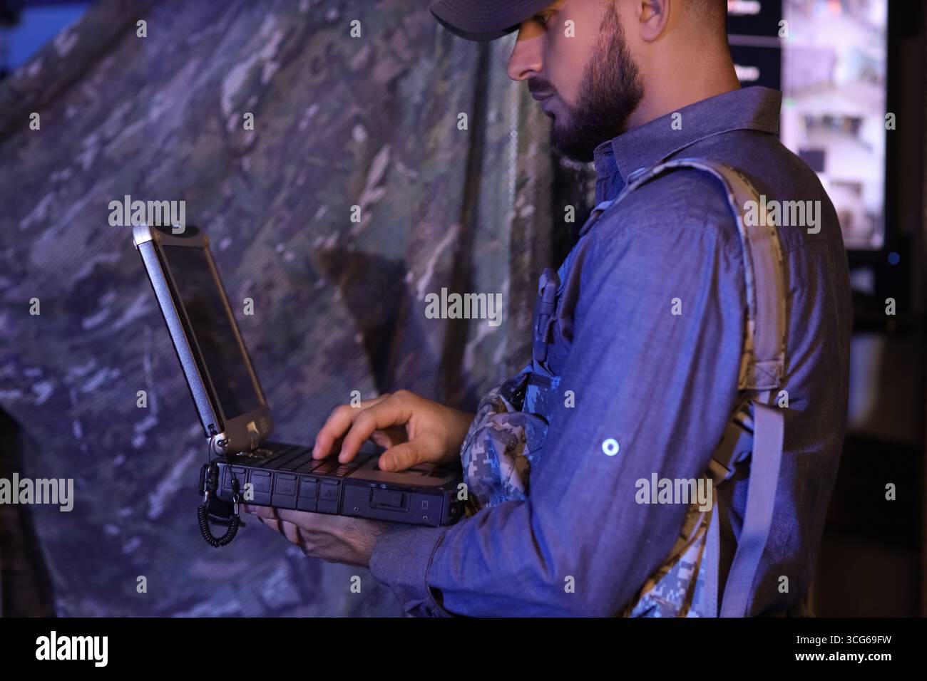Young soldier working with military laptop in command center at night ...