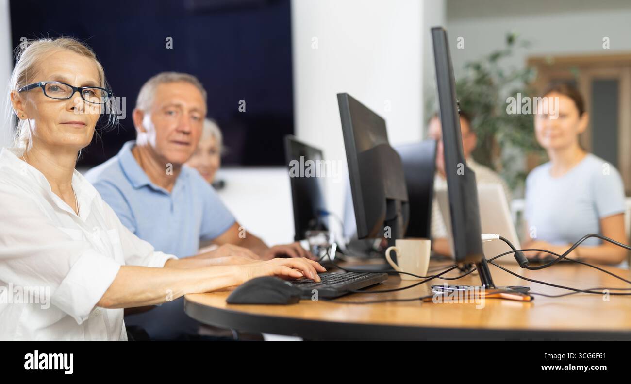 Old woman learning computer programs in training room Stock Photo