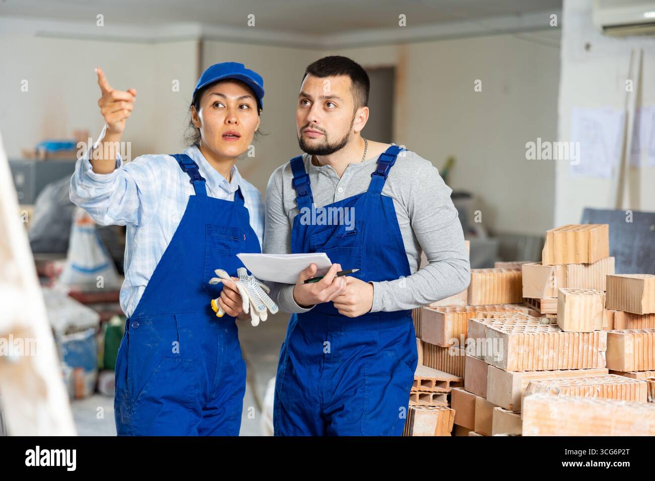 Male and female contractors with papers discussing in building during renovation Stock Photo