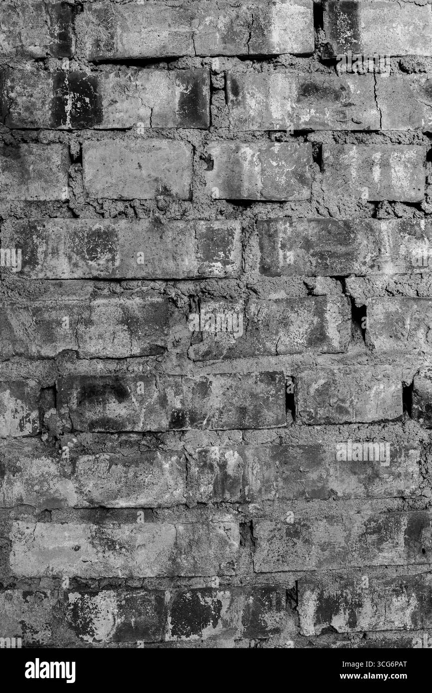 Old brick wall in black and white with rough texture and visible cracks ...