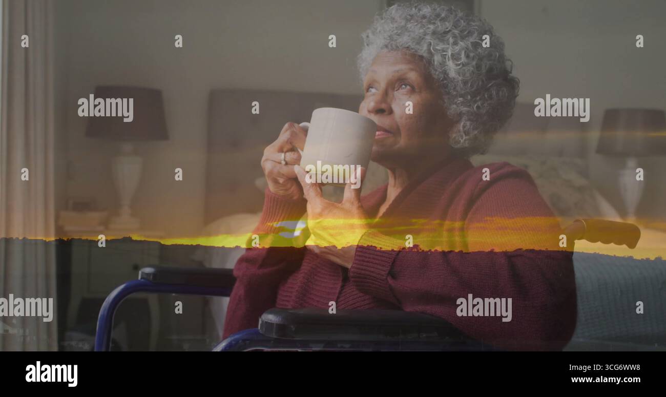 Senior woman in burgundy cardigan sitting in wheelchair drinking from ceramic mug in bedroom Stock Photo