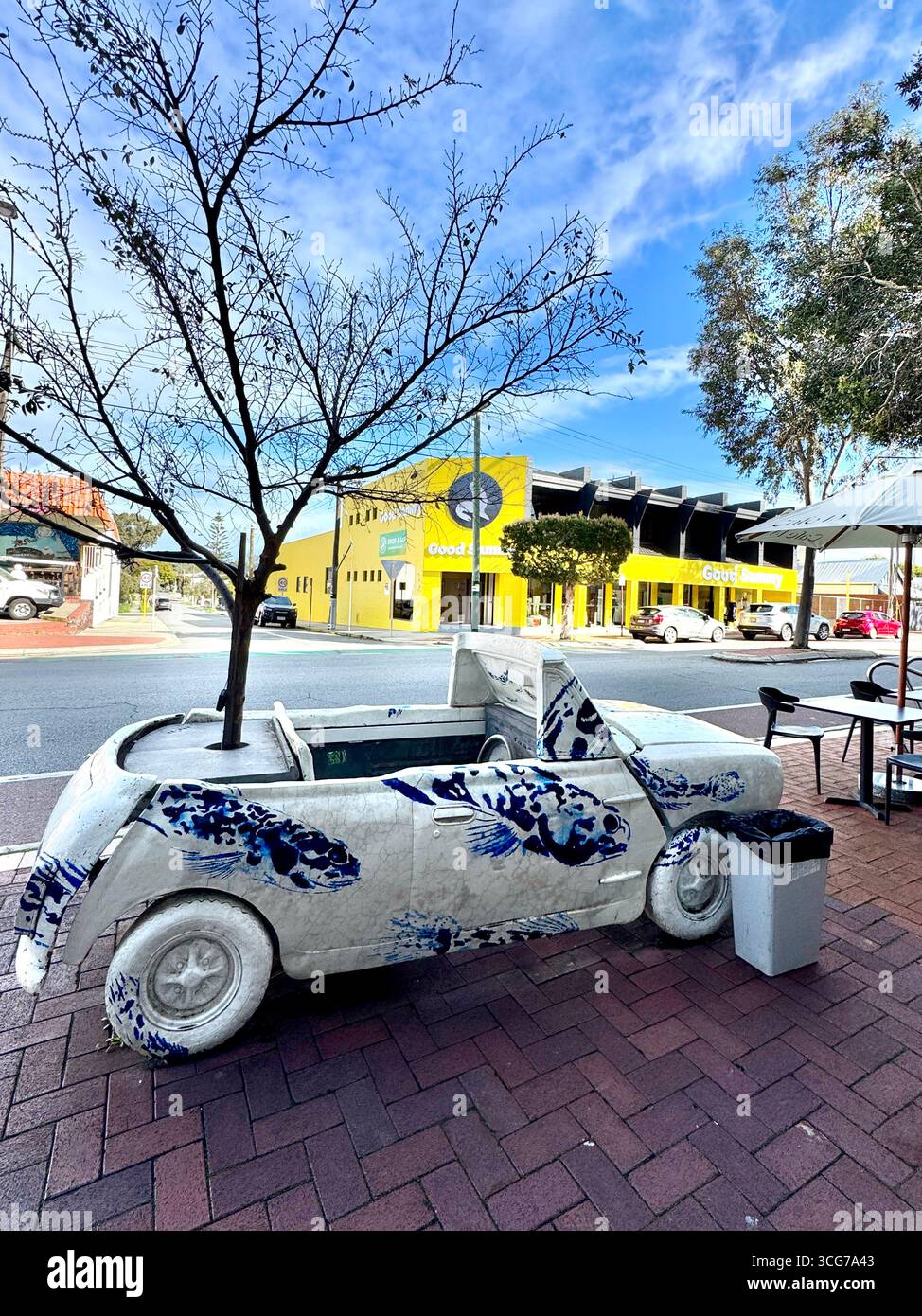 Public art car Aston Mini sculpture by Artitecture with a tree growing through it located on Oxford Street Leederville Perth Western Australia - Smartphone Captured Stock Image