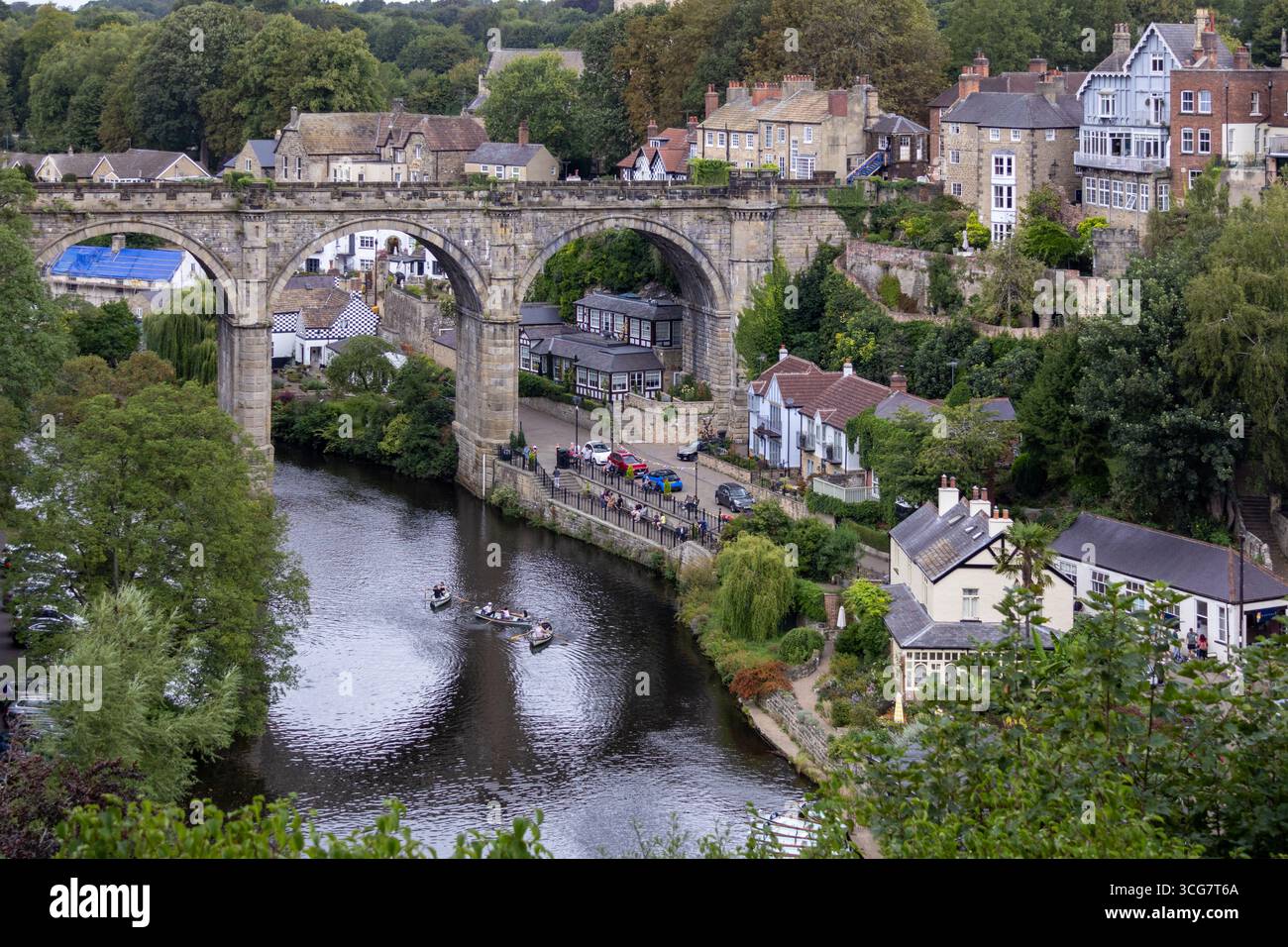 Large arched stone viaduct crossing a calm river, with houses and shops ...