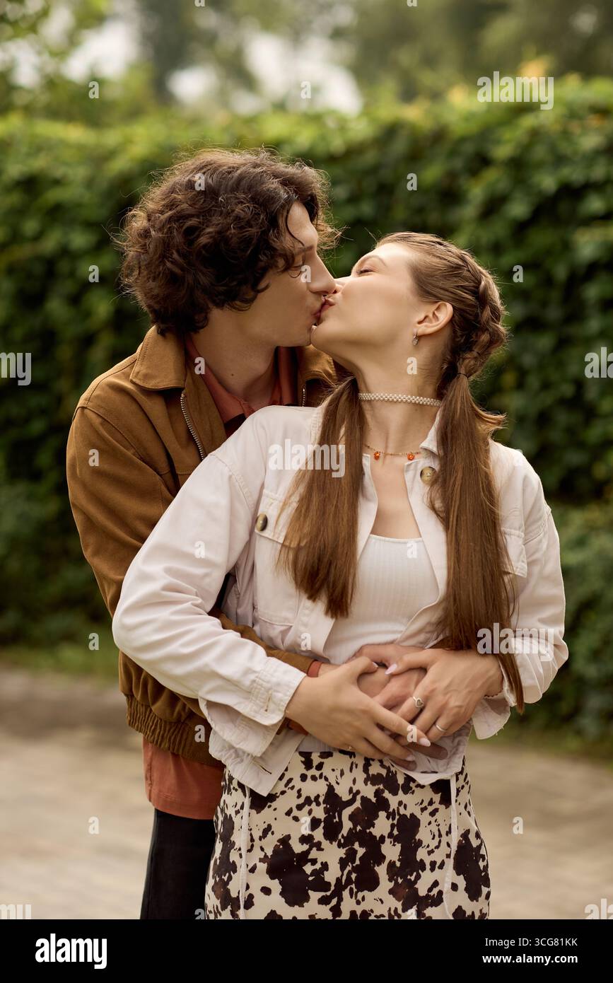 Loving young couple embraces passionately while enjoying a romantic walk outdoors in a park. Stock Photo