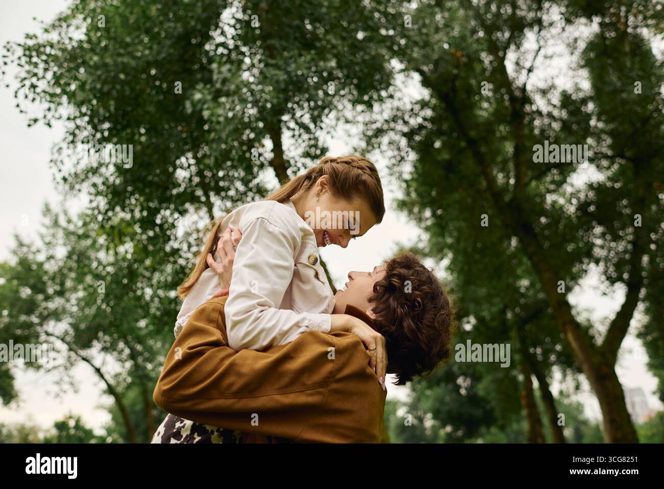 A joyful couple takes a leisurely stroll through the park, cherishing their loving bond. Stock Photo
