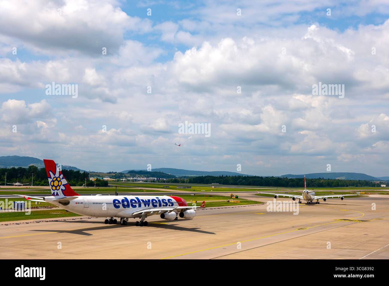 Edelweiss Airlines a nd Other Passenger Airplane Taxiing on Runway and Taking Off in a Sunny Summer Day From the Airport in Kloten, Zurich, Zurich Can Stock Photo