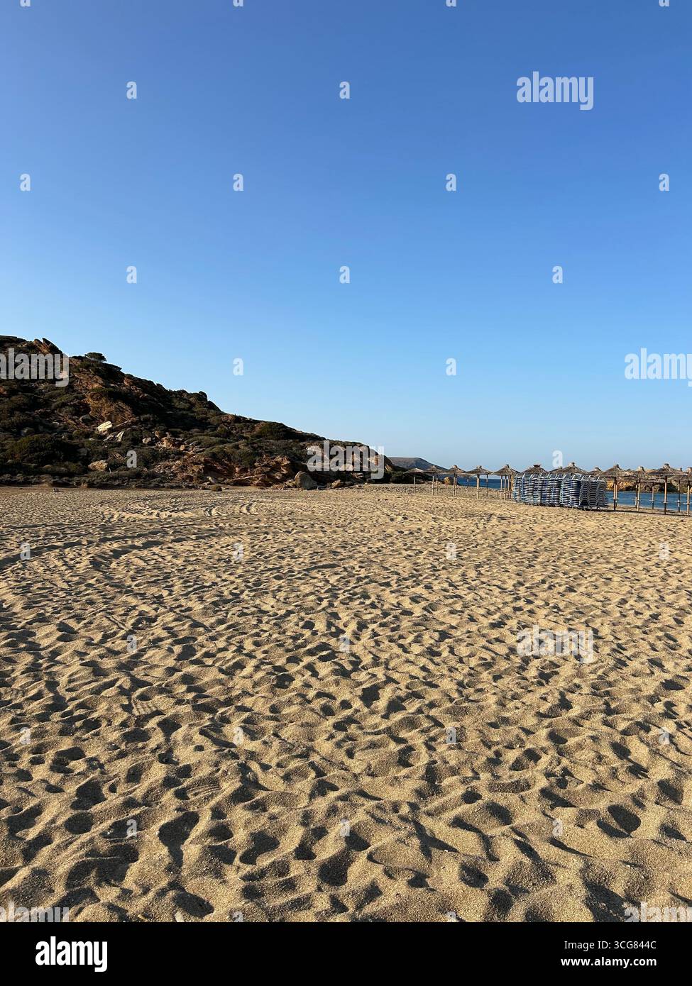 Rocky cliffs with pine trees and a hidden pebble beach along the coastline of Crete, Greece. - Smartphone Captured Stock Image