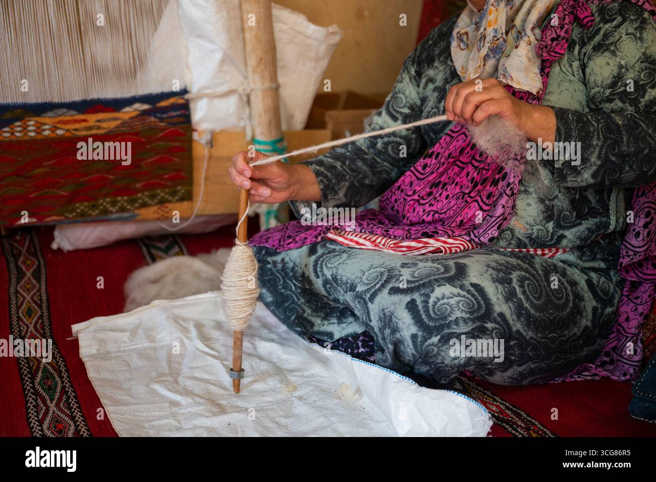 A woman spinning yarn in a rug-making workshop in Morocco Stock Photo ...